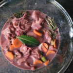 Glazen kom met groente, kruiden, vlees en rode wijn